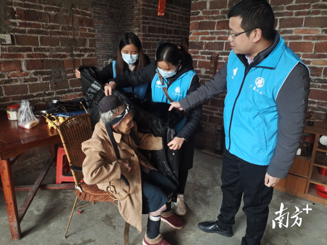 連南瑤族自治縣香坪鎮(zhèn)社工站為困難高齡老人送去御寒棉衣，并幫老人穿上棉衣。